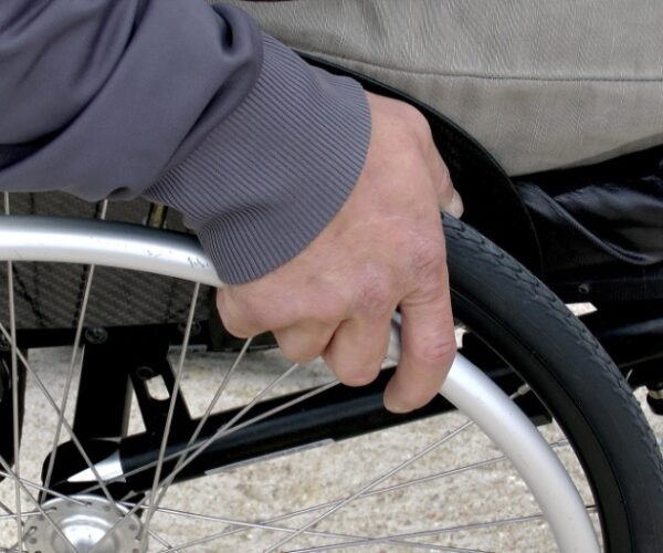 Close up view of hand on a wheelchair wheel.