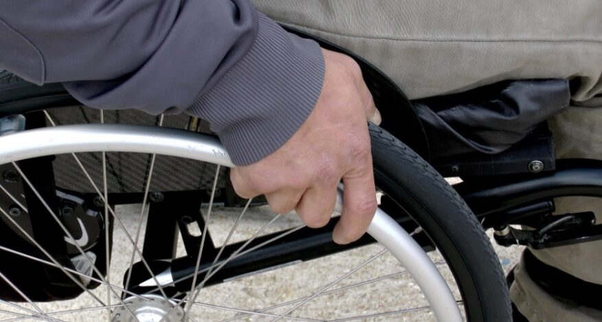 Close up view of hand on a wheelchair wheel.
